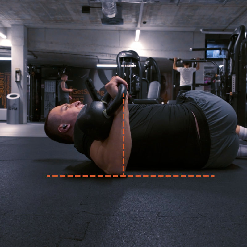 Kettlebell armbar press w leżeniu bokiem na siłowni — wyciskanie kettla ku sufitowi, pionowa linia łokcia